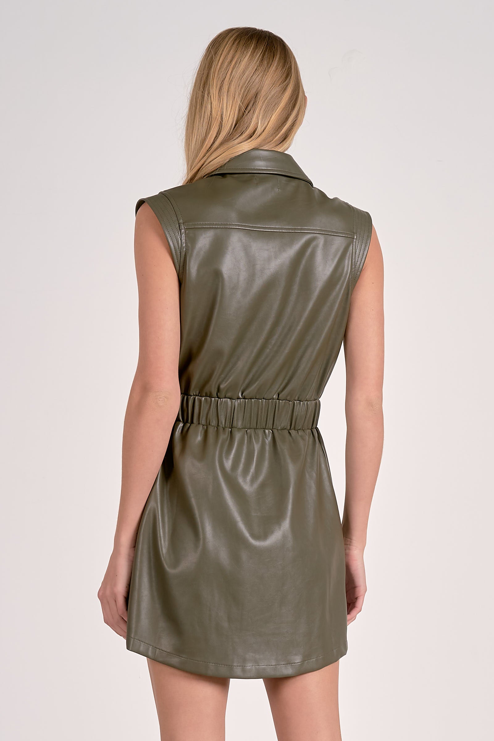 Woman showing back of the pine faux leather elastic waist short dress with collared neckline