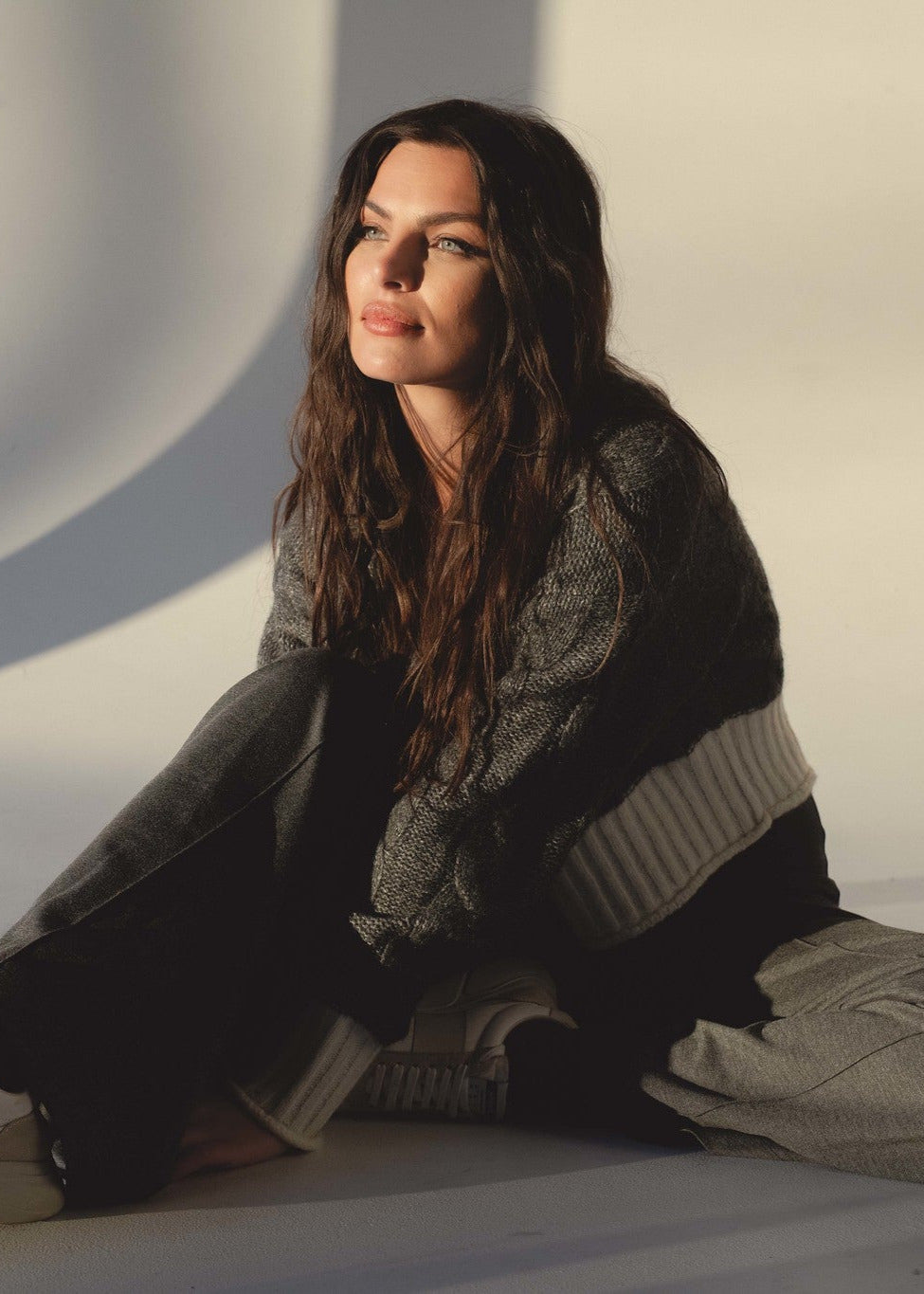 woman sitting on the ground wearing the grey and white cardigan and grey pants from Mainstream Bloomington