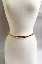 Gold stretch belt with oval buckle styled at the waist
