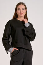 Black mixed media crewneck sweatshirt with striped woven back front view and showing the contrast cuffs