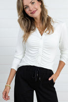 Woman showing a close up of the ivory Mac and Me ruched front button down top