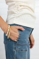 Showing the bottom of the top not tucked into her denim.  The ruching on the side shows the way it fits the body and the ribbed details show how it creates a slimming effect.