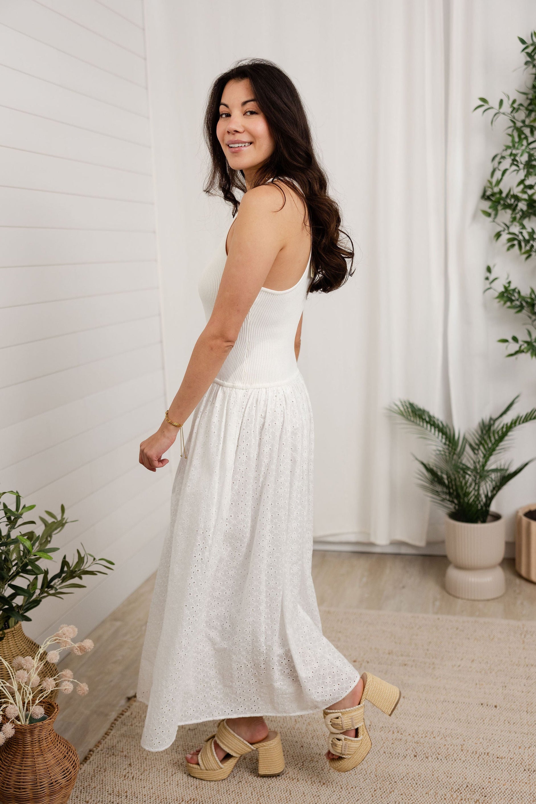 model turning to the back in white mixed media eyelet dress