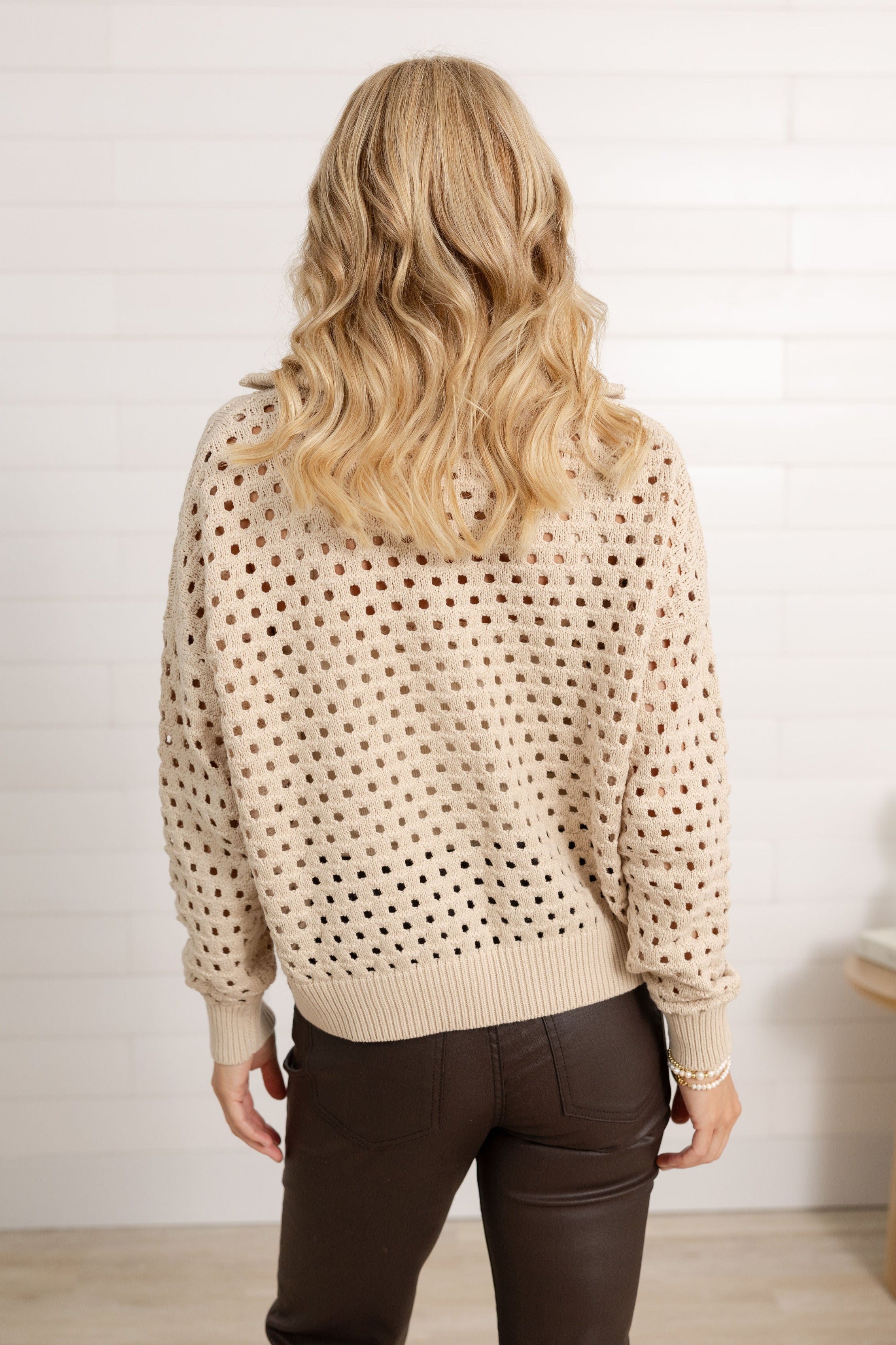 Woman showing the back side of the open knit sweater from Mainstream Boutique Bloomington.