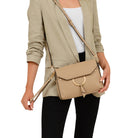 A woman holding the wristlet of the Portia Crossbody as well as the adjustable shoulder strap on the purse