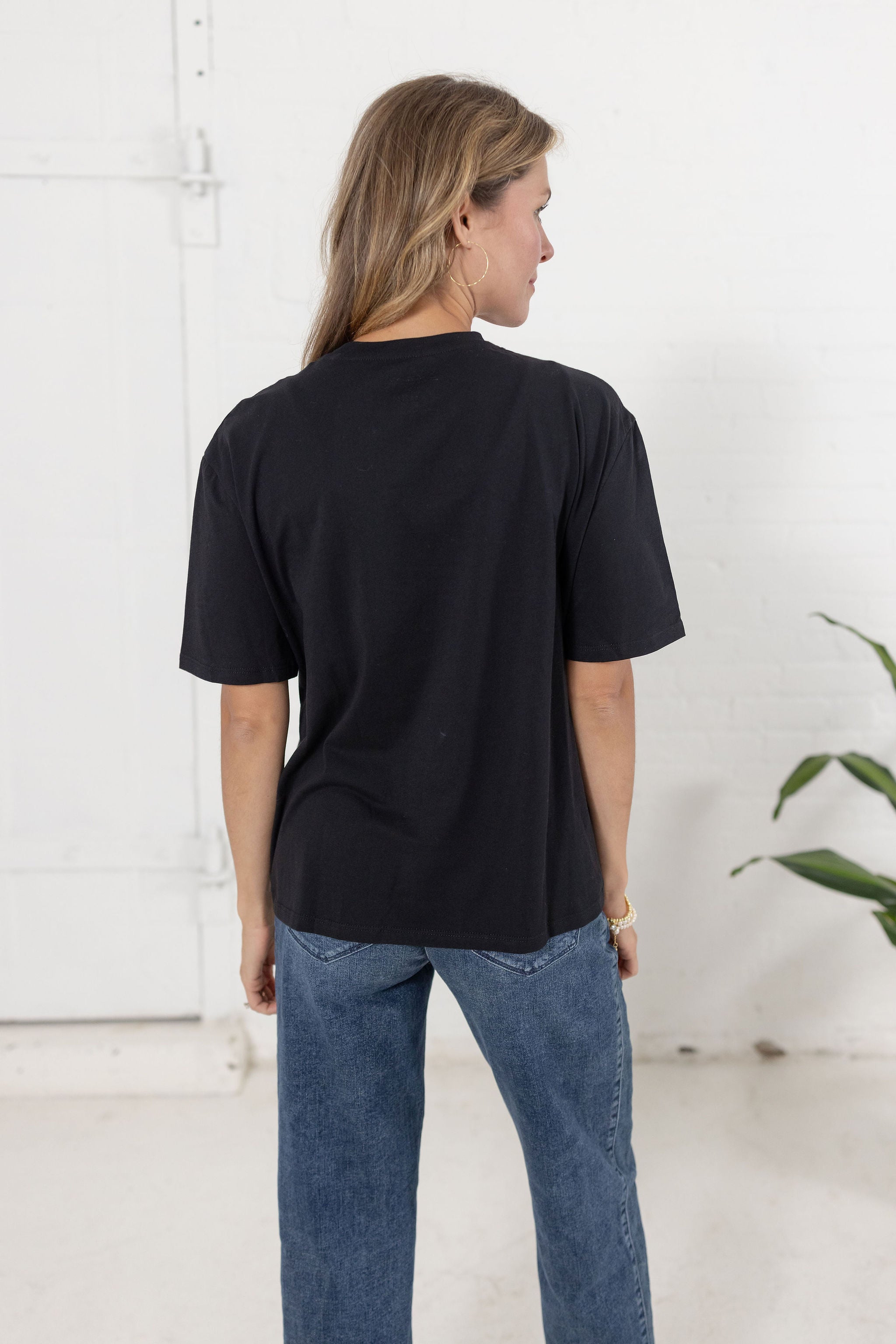 Model showing the back of The Soirée Tee in black with rhinestone embellished neckline from Mainstream Boutique Bloomington