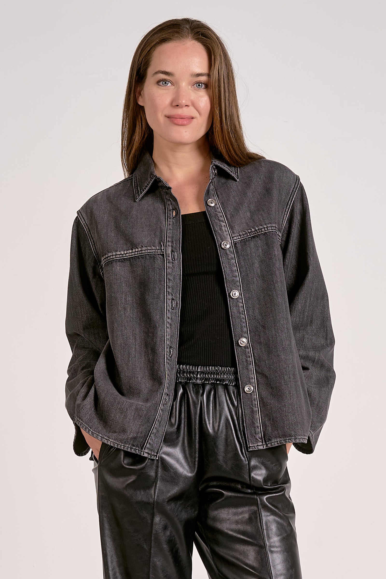 Woman showing the front view of black wash shirt jacket with silver buttons