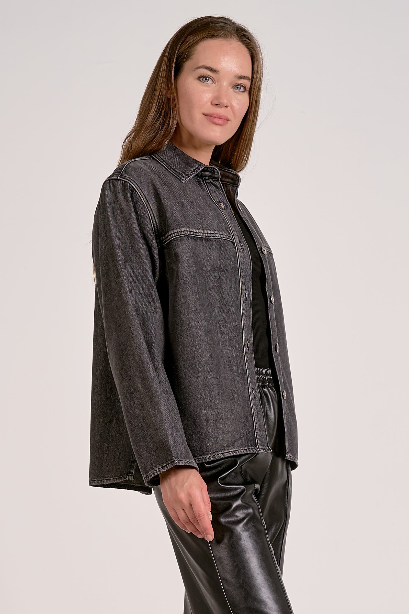 Woman showing the side view of black wash shirt jacket with silver buttons