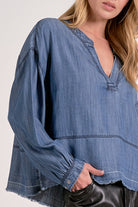 Close up photo of the pullover v-neck, blue wash denim top