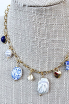 close up of blue and white porcelain charm necklace on gold chain