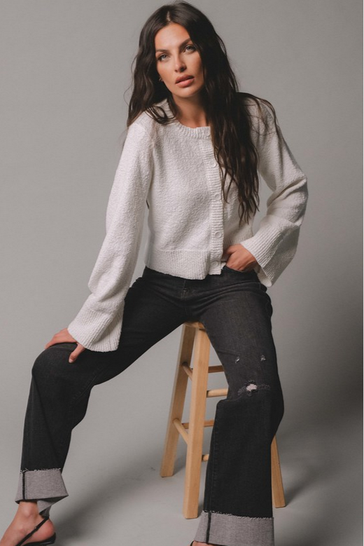 Woman modeling the ivory cardigan with cuff bottom jeans