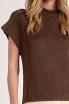 Woman showing details on the cocoa crewneck sweater with cap sleeves.