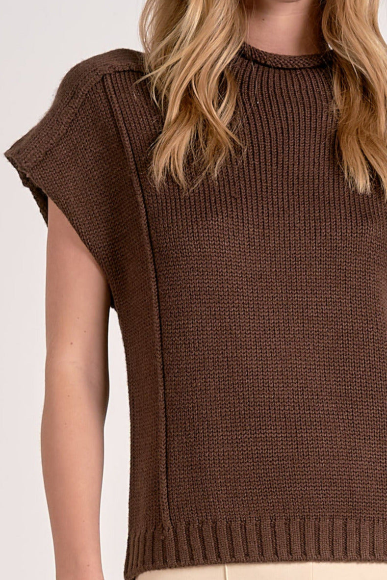 Woman showing details on the cocoa crewneck sweater with cap sleeves.