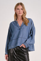 Front view of a woman wearing a washed denim V-neck pullover showing long sleeves, relaxed fit, and frayed hem

