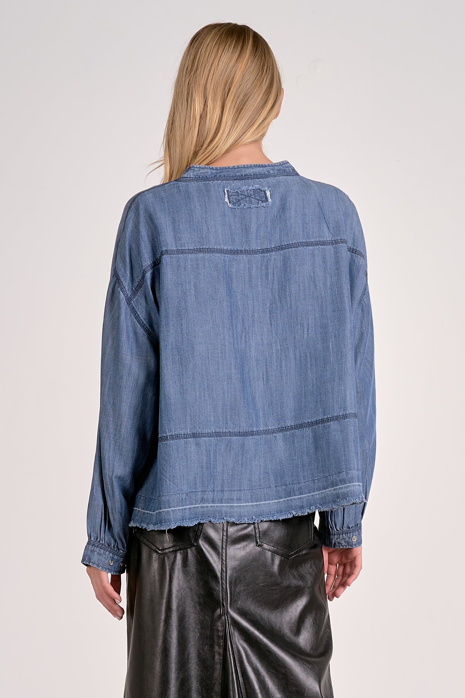 Back view of washed denim V-neck pullover showing long sleeves, relaxed fit, and frayed hem