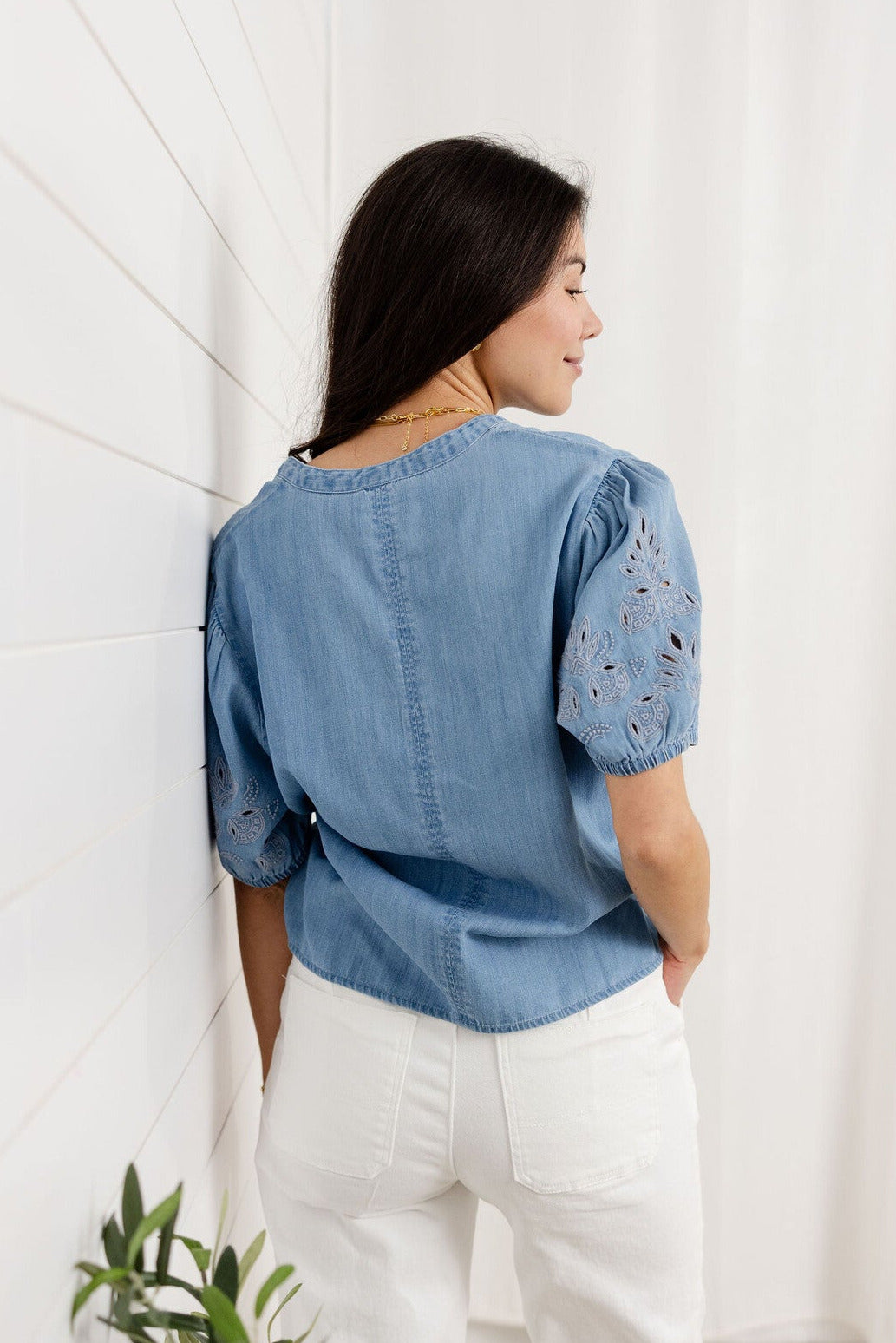 woman showing back of chambray v-neck embroidered sleeve top