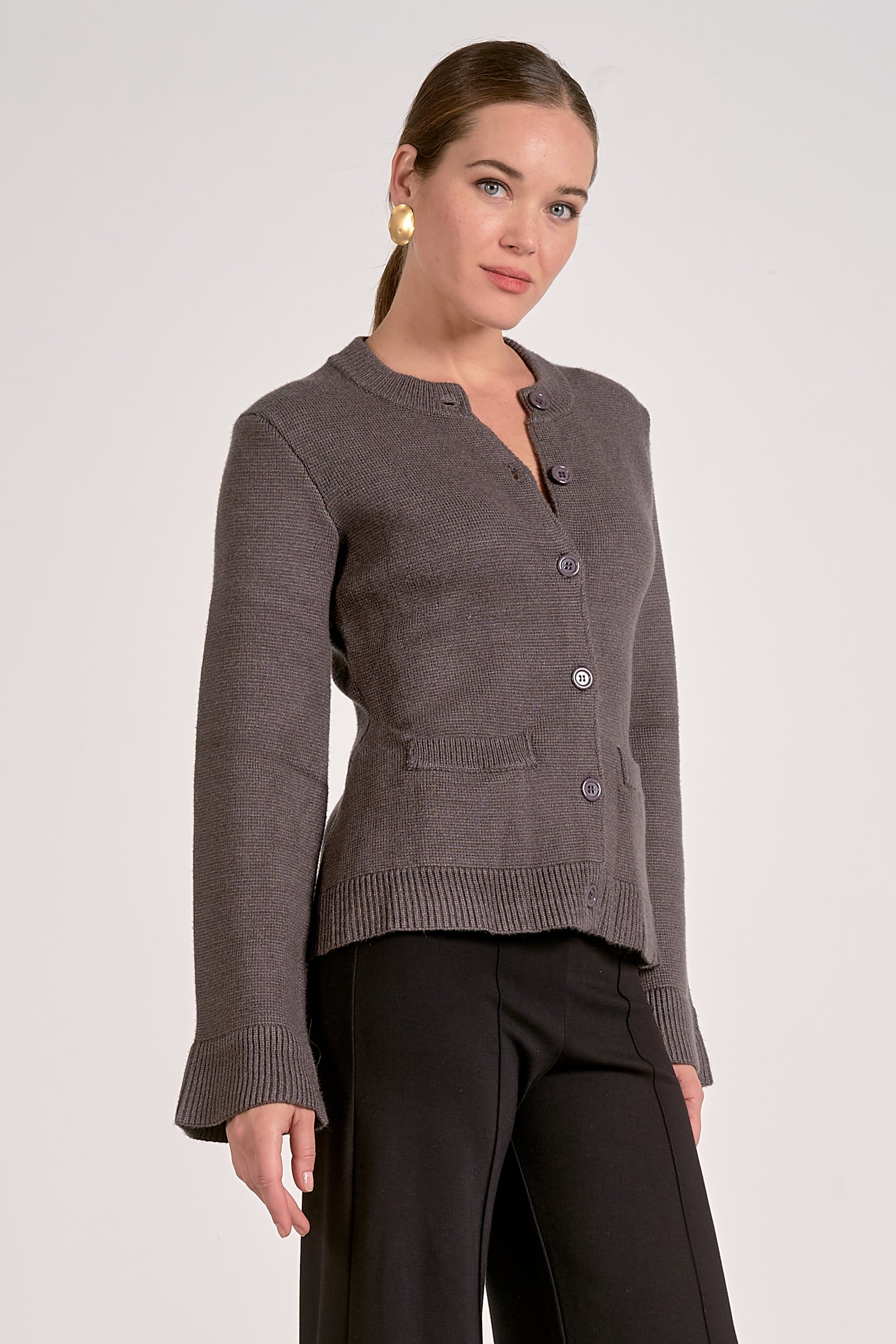 Woman showing the side view of the graphite flare cuff button cardigan 