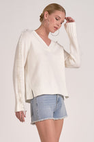 Model showing side of Willow Fringe V-Neck Sweater in ivory white with fringe trim sleeves from Mainstream Boutique Bloomington