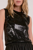 Woman showing the details on the black sequin tank top from Mainstream Boutique Bloomington.