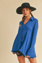 Woman wearing a blue shirt and black hat against a beige background