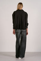 Woman wearing an outfit highlighting the back of the grey wash sweatpant jeans.