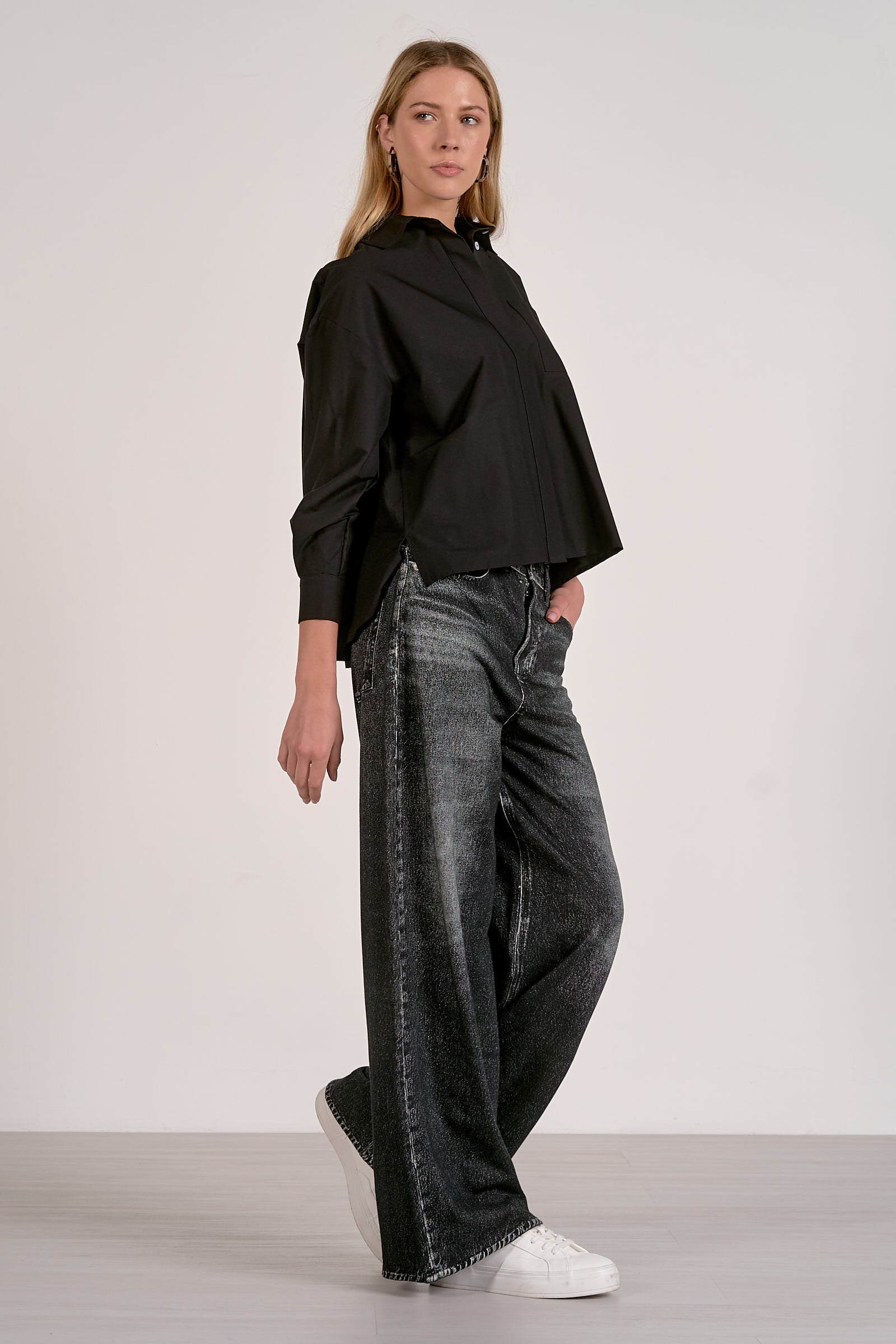 Woman showing the side of the grey wash sweatpant jeans.