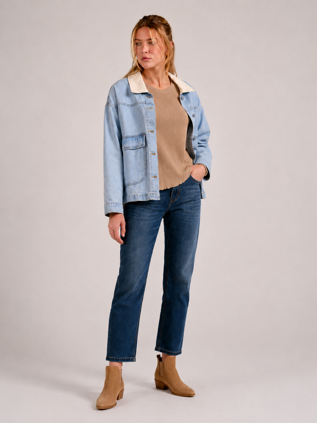 woman modeling light blue denim jacket, with cream contrast collar, tan waffle knit top, and darker jeans with tan booties