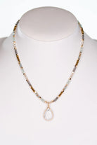 Multi-colored crystal bead necklace displayed on jewelry stand with marble teardrop pendant.