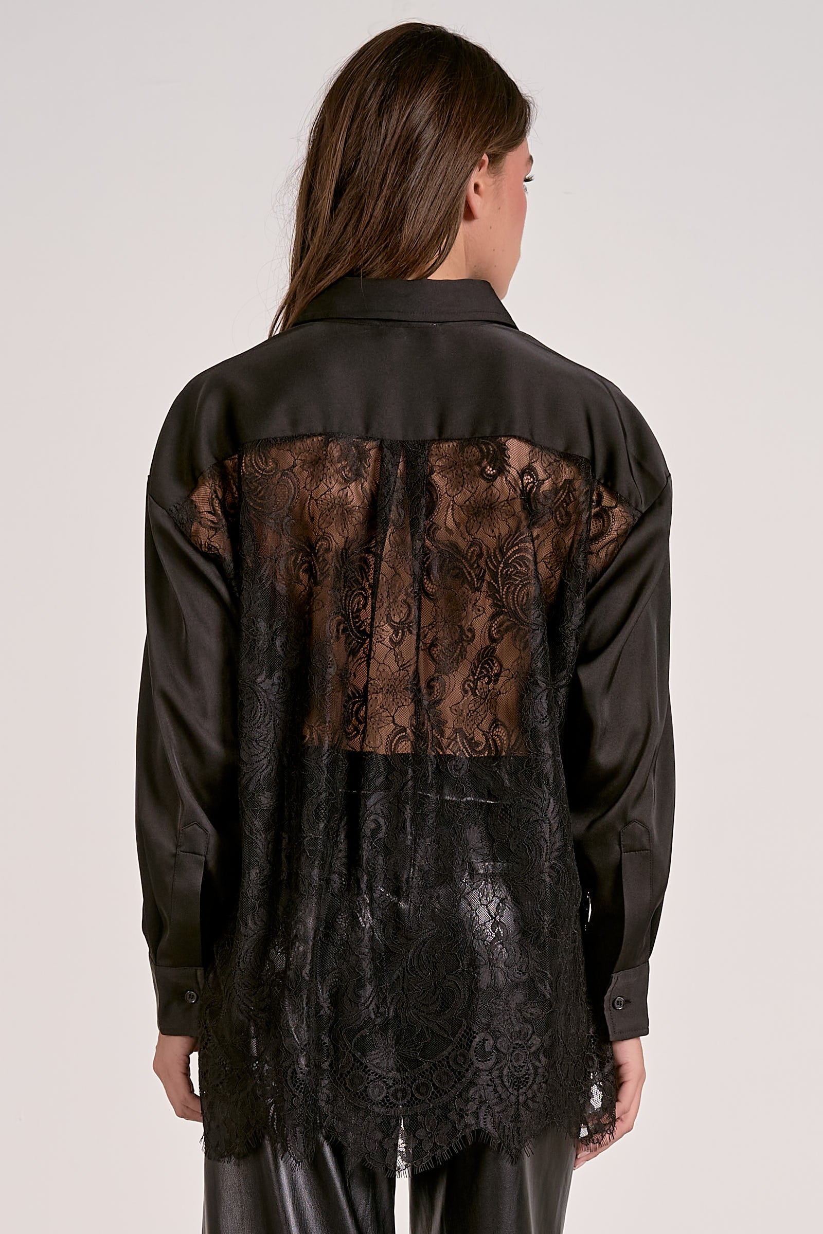 Model showing the back of the black satin button down blouse with lace back detail