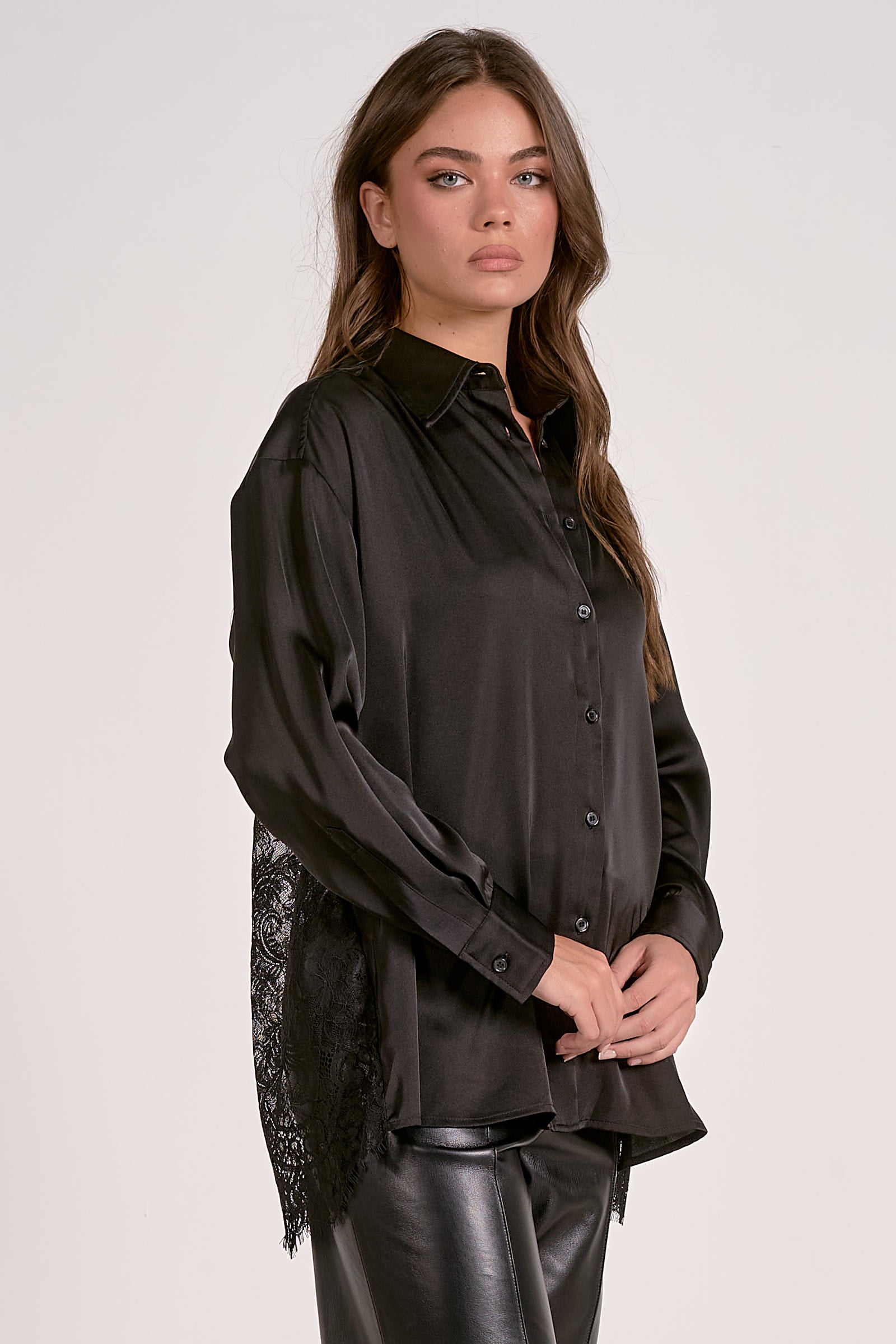 Model showing the side of the black satin button down blouse with lace back detail