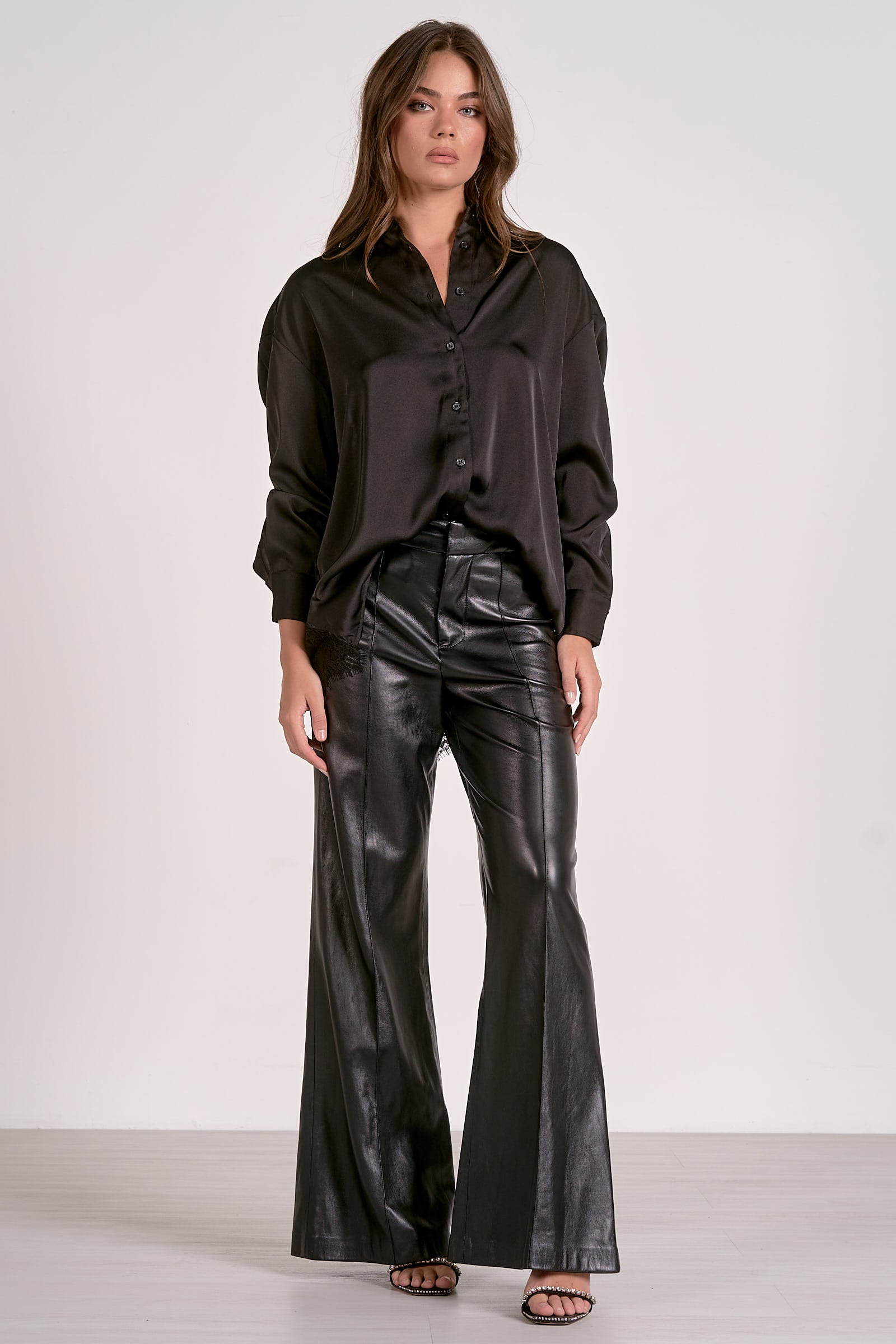Model showing one way o style the black satin button down blouse with lace back detail