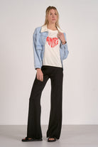 Full outfit view of light blue denim jacket styled with graphic tee and black pants.