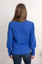 Mac modeling the back of the gathered shoulder top in blue