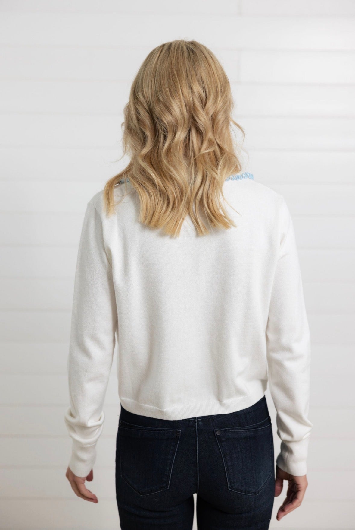 back of Mac and Me ivory ruffle collar sweater with blue lettuce trim worn with dark denim