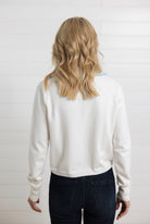 back of Mac and Me ivory ruffle collar sweater with blue lettuce trim worn with dark denim