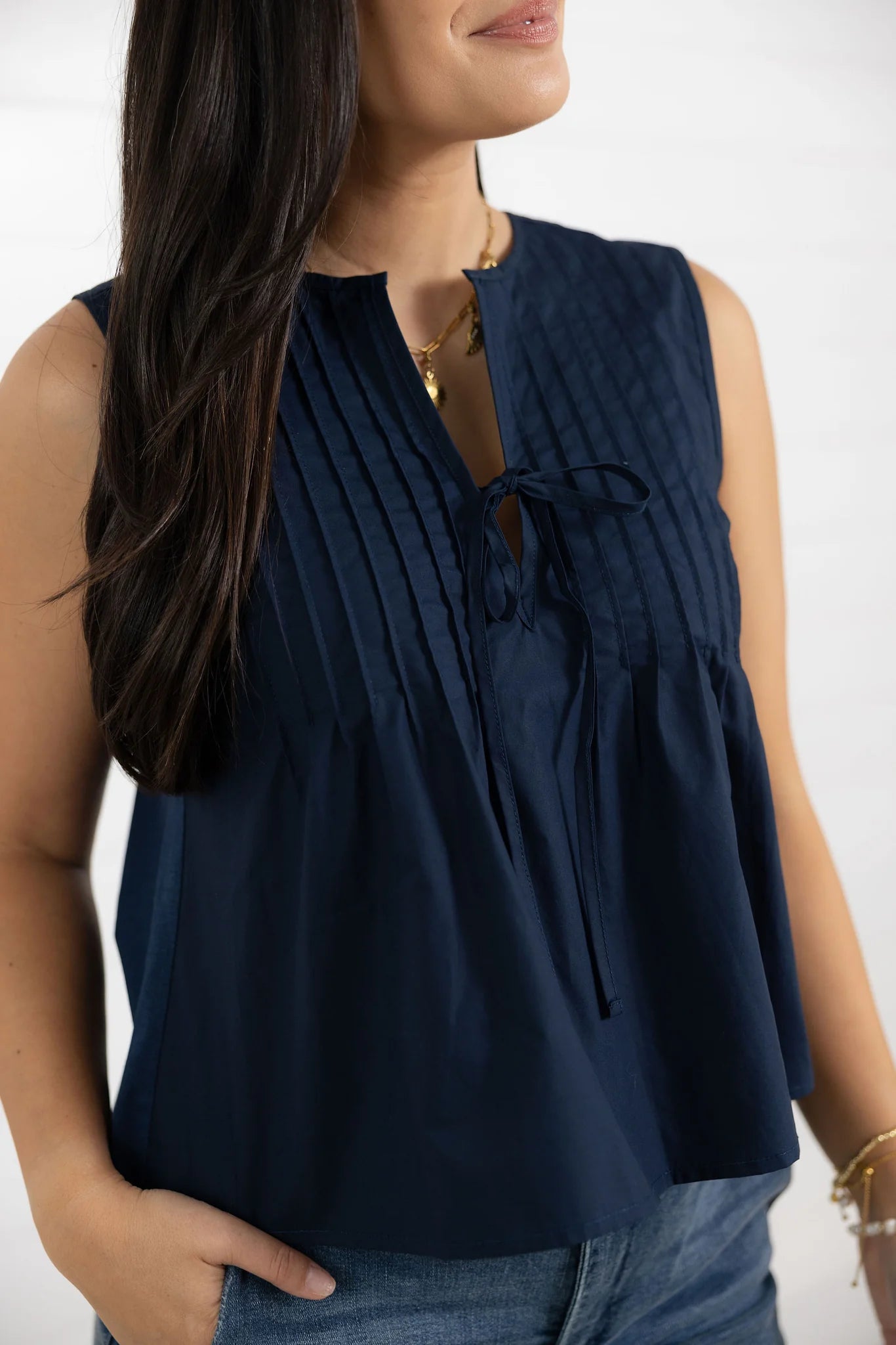 Navy sleeveless blouse with tie neckline on model
