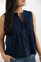 Navy sleeveless blouse with tie neckline on model