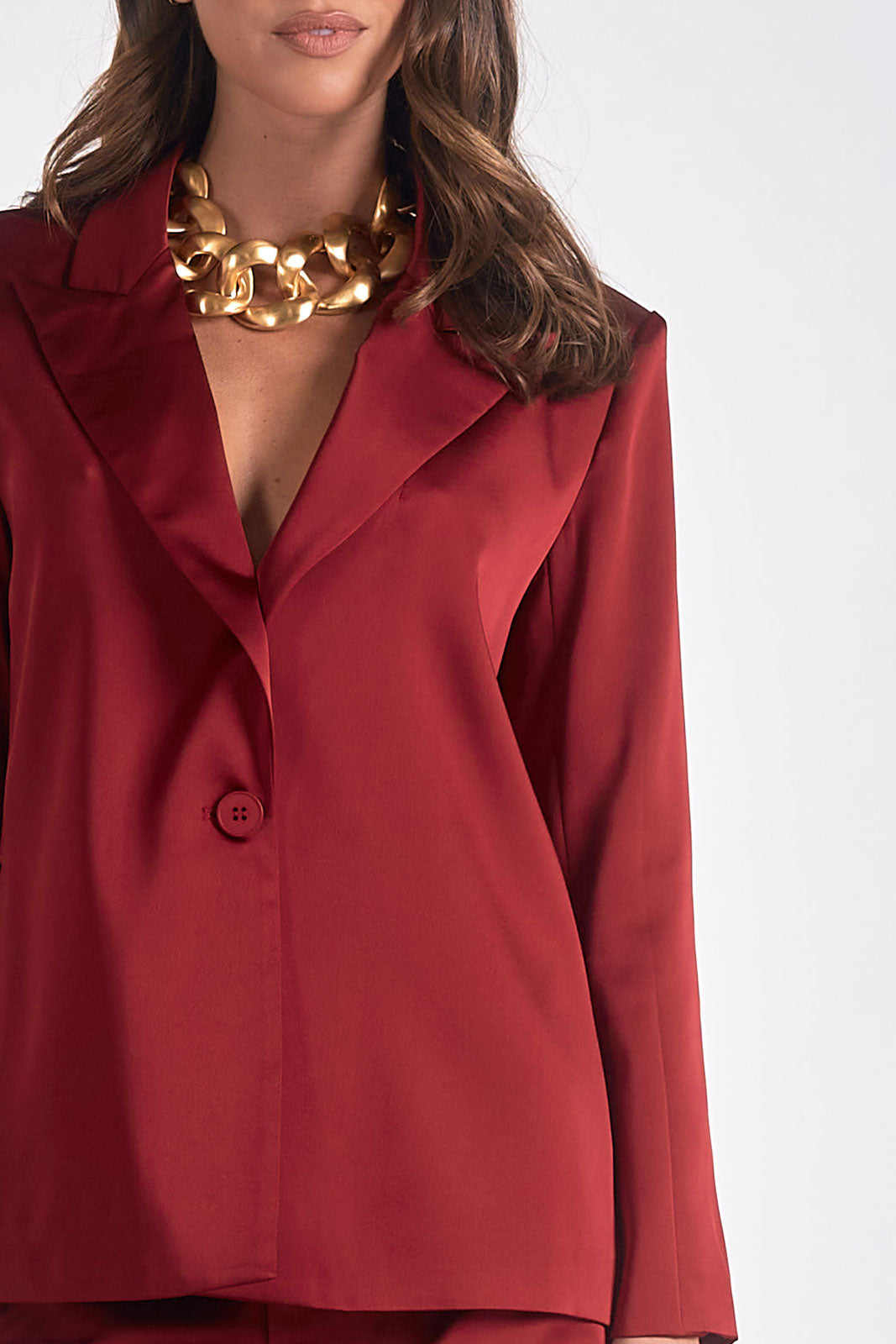 close up detail of maroon satin tailored blazer on hanger with structured silhouette