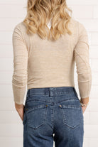 woman modeling the back of the mock neck side ruched top in brushed tan
