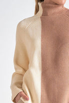 A woman showing the details on the colorblock sweater with creamy ivory and soft beige vertical blocks