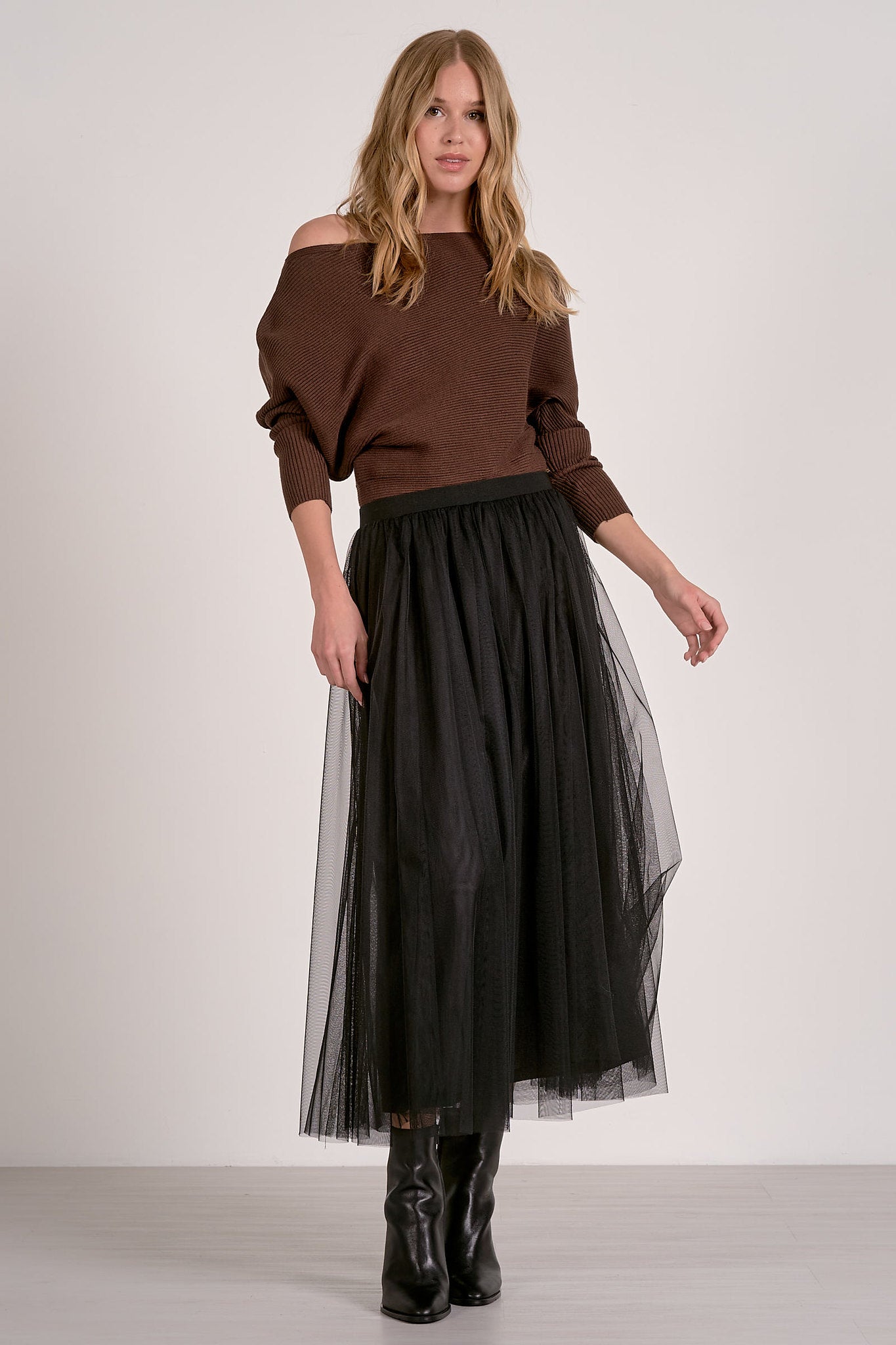 model wearing dark chocolate off shoulder ribbed sweater with dolman sleeves and black tulle skirt
