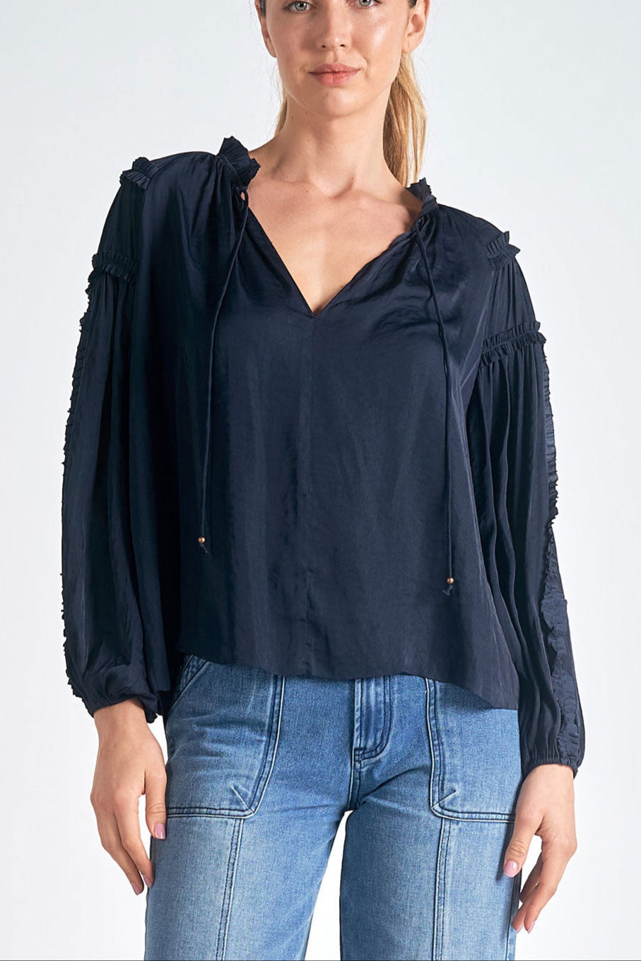 a woman wearing a navy long sleeve top with denim jeans