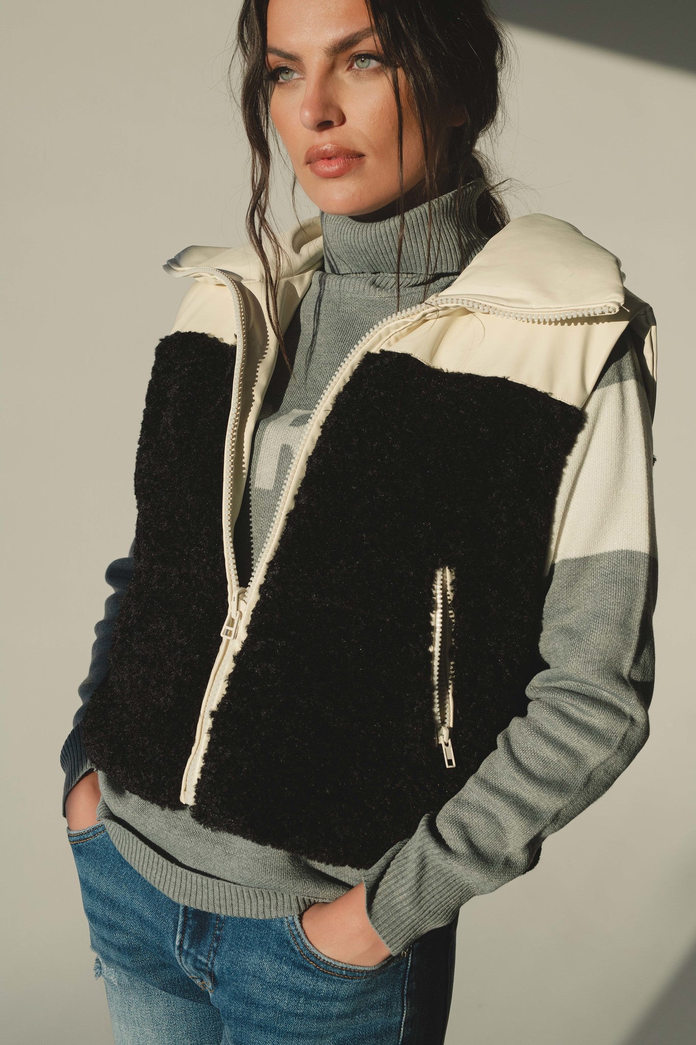 Woman wearing black and cream reversible sherpa vest with grey sweater