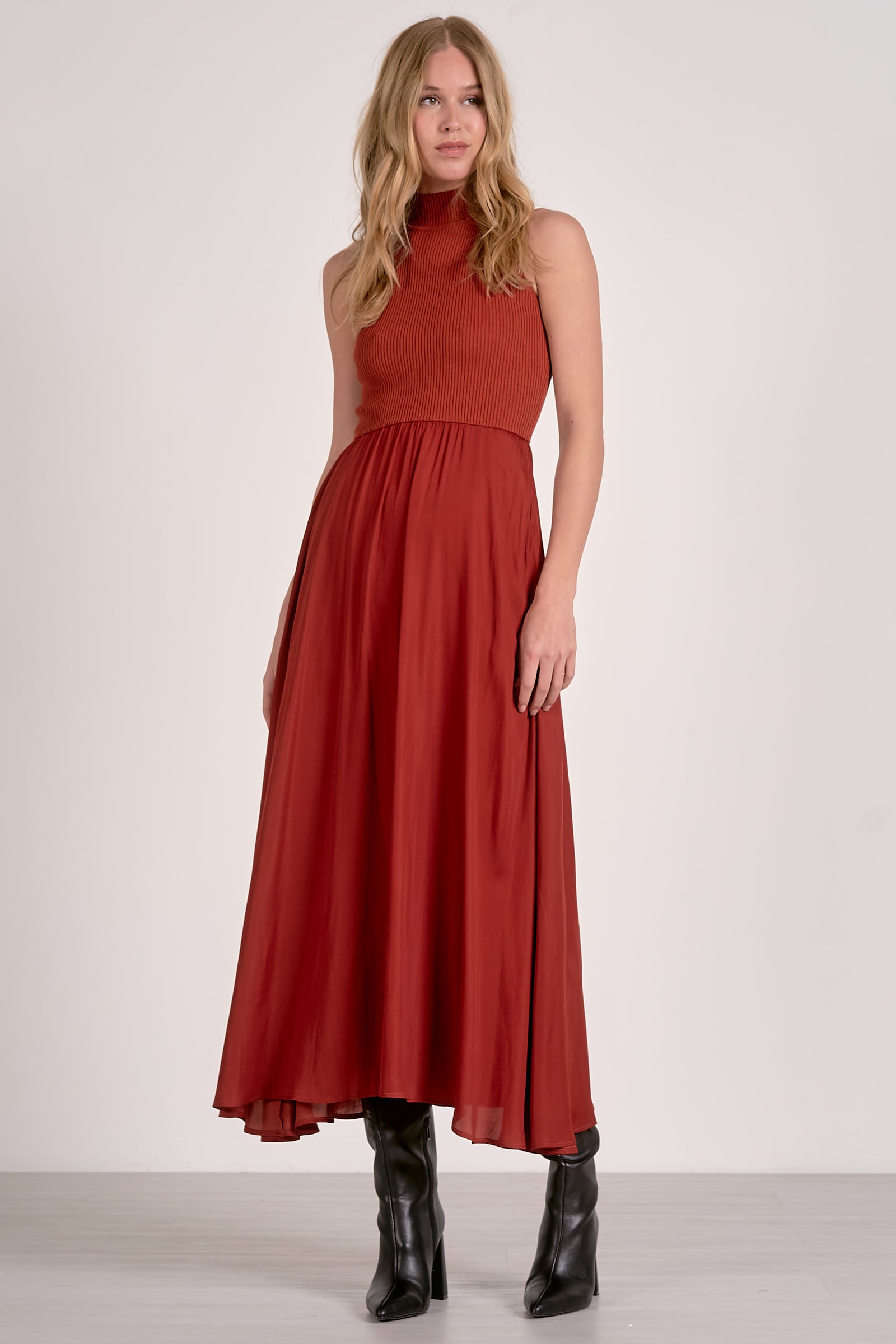 Model wearing rust mockneck sleeveless maxi dress with ribbed bodice, woven skirt, and high-low hem from Mainstream Boutique Bloomington