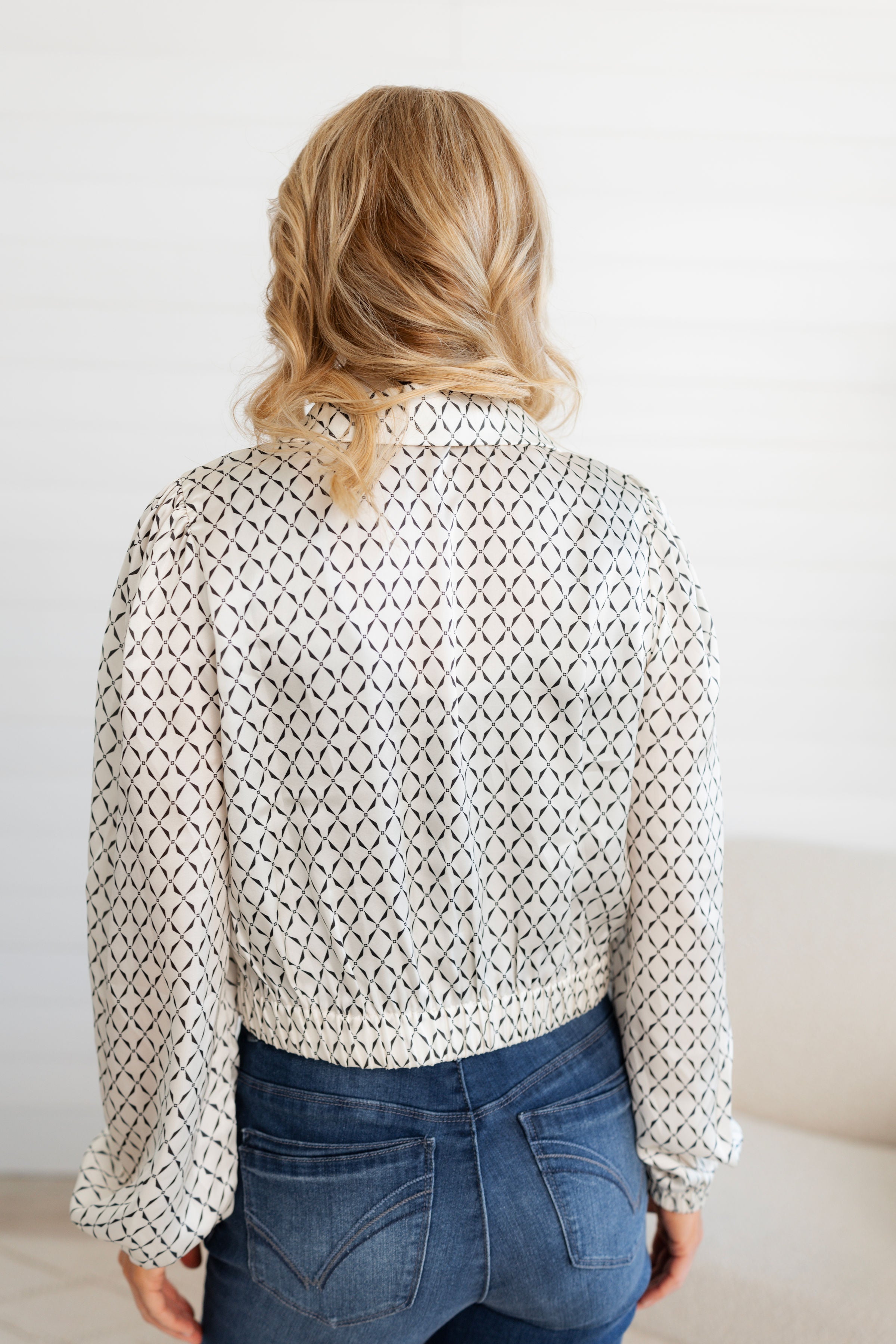 Woman showing the back of the Ivory Scarf Blouse with Gold Ring Detail from Mainstream Boutique Bloomington
