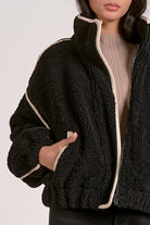 woman wearing a black sherpa bomber jacket with contrast trim 