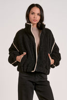 woman wearing a black sherpa bomber jacket with contrast trim 