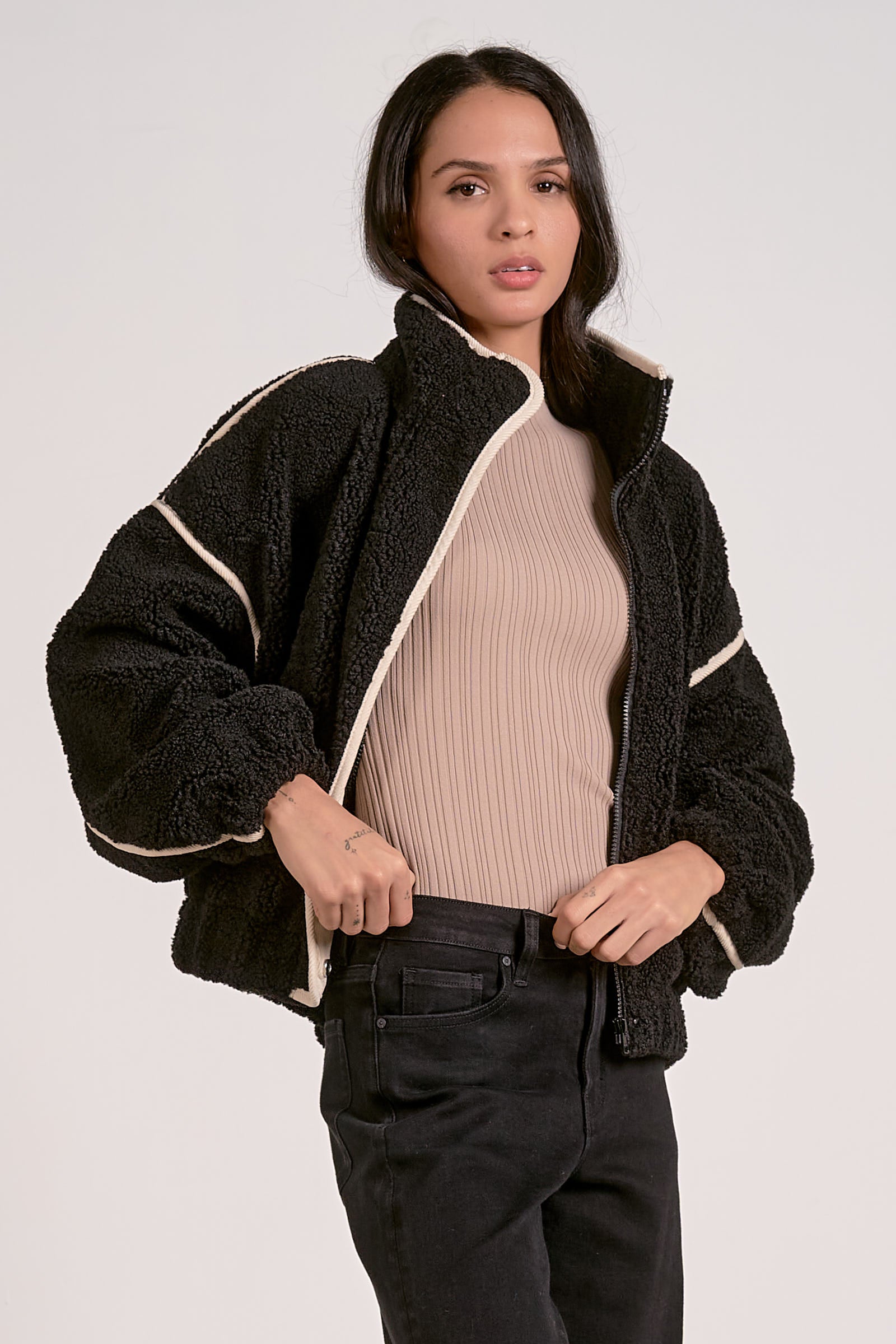 woman showing the side of the black sherpa bomber jacket with contrast trim 
