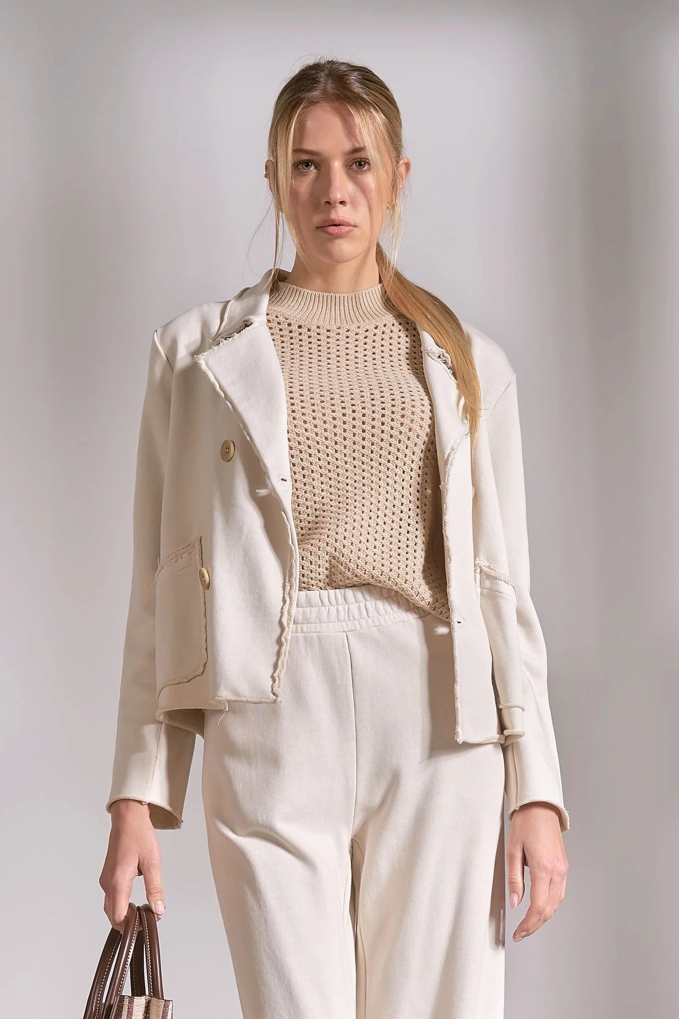 Stone knit blazer worn open with neutral sweater and trousers