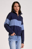 Woman wearing a quarter zip color block sweater navy and light blue stripes in front view